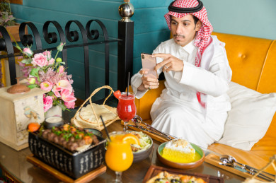 صورة مقربة لمائدة طعام خاصة برجل سعودي خليجي ، يقضي اجواء رائعة  في المطعم ، العديد من أصناف الطعام و الماكولات على الطاولة ، متجر و مطعم سعودي