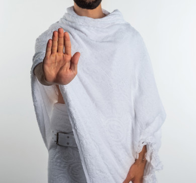 بورتريه لرجل مسلم عربي سعودي خليجي بلباس الاحرام   ، يرفع يده ليتجنب المصافحة واقتراب الاخرين منه ، تجنب انتشار العدوى ، الحفاظ على المسافات ،  الاستعداد لأداء العمرة ،  اداء الفرائض الدينية ، اسلاميات و عبادة ، فريضة الحج ، خلفية بيضاء