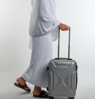 بورتريه لرجل مسلم عربي سعودي خليجي بلباس الاحرام   ، يجر حقيبه السفر ، الاستعداد لأداء العمرة ،  اداء الفرائض الدينية ، اسلاميات و عبادة ، فريضة الحج ، خلفية بيضاء