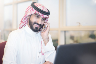 رجل اعمال سعودي خليجي على مكتب ، يتحدث بالهاتف المحمول ، لباس السعودي التقليدي  ، شركة سعودية ، عمل الخليج ، وظيفة مكتبية ، بيئة عمل
