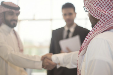 رجل اعمال سعودي مع شركاء عمل متعددي الثقافات يتصافحون في المكتب ، بيئة عمل ، شركة سعودية 
