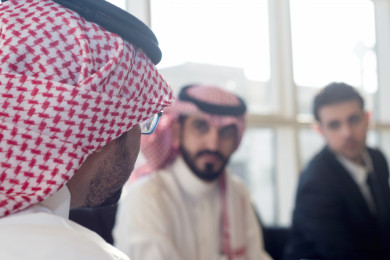 رجل اعمال سعودي مع شركاء عمل متعددي الثقافات يتصافحون في المكتب ، بيئة عمل ، شركة سعودية 