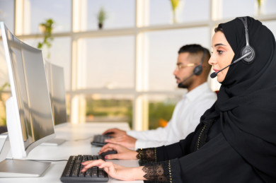 شابة موظفة عربية سعودية  و شاب موظف عربي سعودي في بيئة العمل , زملاء عمل ، العمل بالدعم الفني عبر الكمبيوتر