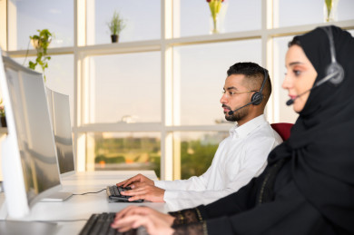 شابة موظفة عربية سعودية  و شاب موظف عربي سعودي في بيئة العمل , زملاء عمل ، العمل بالدعم الفني عبر الكمبيوتر