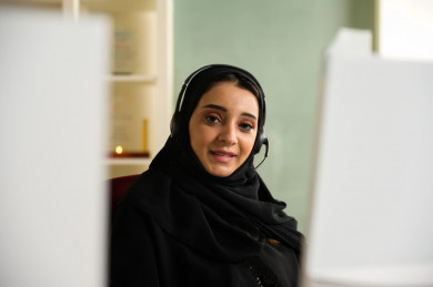 موظفة سعودية شابة في بيئة العمل , تعمل بالدعم الفني عبر الكمبيوتر 