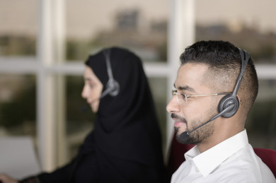 صورة مقربة لشابة موظفة عربية سعودية  و شاب موظف عربي سعودي في بيئة العمل , زملاء عمل ، العمل بالدعم الفني عبر الكمبيوتر 