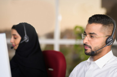 صورة مقربة لشابة موظفة عربية سعودية  و شاب موظف عربي سعودي في بيئة العمل , زملاء عمل ، العمل بالدعم الفني عبر الكمبيوتر 