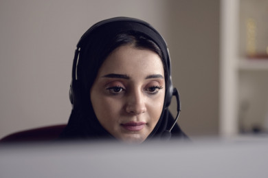 موظفة سعودية شابة في بيئة العمل , تعمل بالدعم الفني عبر الكمبيوتر
