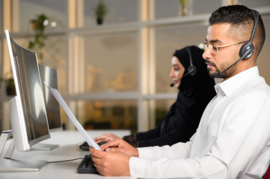 شابة موظفة عربية سعودية  و شاب موظف عربي سعودي في بيئة العمل , زملاء عمل ، العمل بالدعم الفني عبر الكمبيوتر 