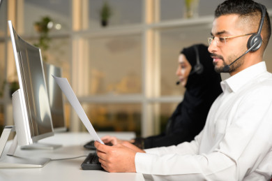 شابة موظفة عربية سعودية  و شاب موظف عربي سعودي في بيئة العمل , زملاء عمل ، العمل بالدعم الفني عبر الكمبيوتر 