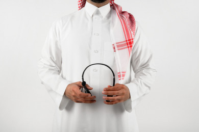 بورتريه رجل سعودي عربي خليجي , لبس سعودي تقليدي ، مع سماعات رأس صوتية  بخلفية بيضاء