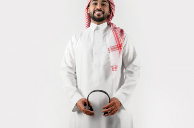 بورتريه رجل سعودي عربي خليجي , لبس سعودي تقليدي ، مع سماعات رأس صوتية  بخلفية بيضاء