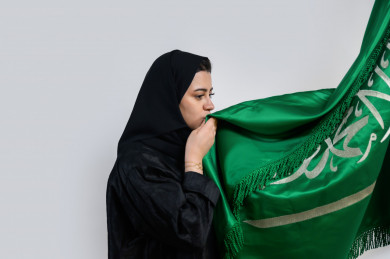 مواطنة سعودية  تقبل علم المملكة العربية السعودية 