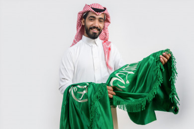رجل  سعودي يمسك علم السعودية في يوم الوطني السعودي 