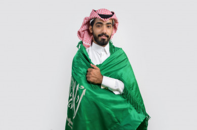 شاب سعودي يضع علم المملكة العربية  السعودية على ظهره 