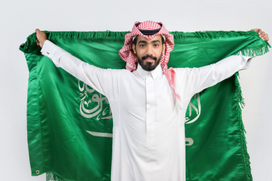 مواطن سعودي يرفع  علم السعودية في يوم الوطني السعودي 