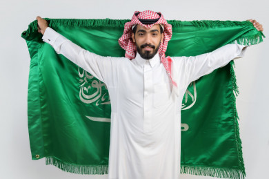 مواطن سعودي يرفع  علم السعودية في يوم الوطني السعودي 