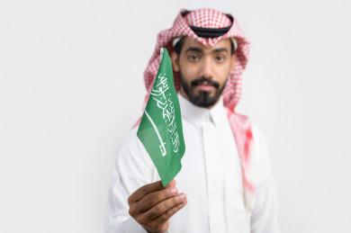 صورة بورترية لشاب سعودي يمسك علم المملكة العربية السعودية 
