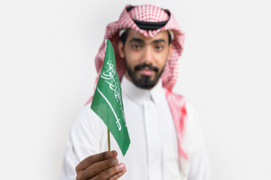 صورة بورترية لشاب سعودي يمسك علم المملكة العربية السعودية 