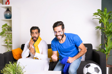 صديقان سعوديان يشاهدان مباراه للدوري السعودي ، احدهم يشجع فريق الهلال و الاخر يشجع فريق النصر ، ايماءات وجه مختلفة ، يجلسان على اريكة في غرفة المعيشة