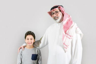بورتريه جد سعودي مع حفيده, كبير بالسن خليجي يرتدي ثوب و شماغ بخلفية بيضاء