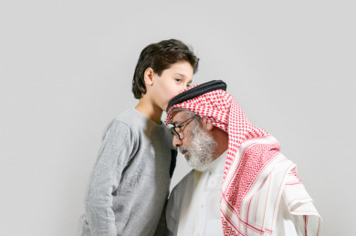 بورتريه طفل سعودي يقبل رأس جده يرتدي تيشيرت بخلفية بيضاء