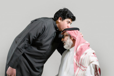 بورتريه شاب سعودي يقبل رأس جده, يرتدي ثوب أسود, بخلفية بيضاء