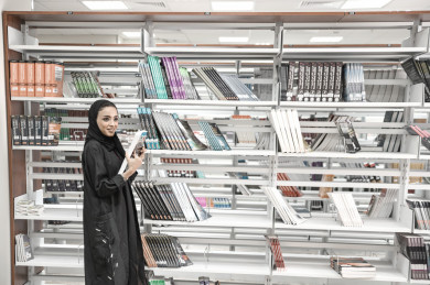 طالبة سعودية في المكتبة ، بنت عربية بالحجاب بيدها كتاب للقراءه ، مجموعة من الكتب في الرفوف بالخلفية  ،طالبة جامعية  ، تعليم جامعي  ، متدربة ، جامعة سعودية ، مشروع جامعي ، قراءه كتب ،  ، الدراسة في المكتبة