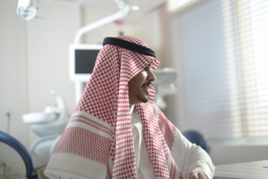 شاب سعودي خليجي عربي يجلس في عيادة خاصة ، موعد الى طبيب الأسنان ، علاج آلام الاسنان