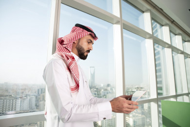 رجل اعمال سعودي خليجي عربي ، يعمل على الكمبيوتر اللوحي الرقمي ، مقر الشركة ، شركة سعودية