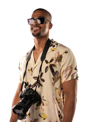 بورتريه لشاب اسمر عربي خليجي سعودي يرتدي نظارة شمسية، مصور فوتوجرافي يرتدي ملابس كاجوال يحمل كاميرا عالية الدقة، جلسات تصوير، هواية التصوير، بشرة سمراء، خلفية بيضاء