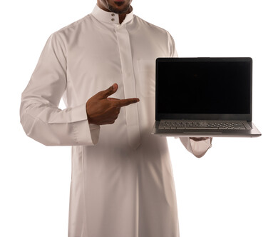 بورتريه لشاب أسمر عربي خليجي سعودي يشير الى الجهاز المحمول، شاشة سوداء مفرغة، تسويق رقمي الكتروني، استخدام تقنيات حديثة، اعلانات، بشرة سمراء، خلفية بيضاء