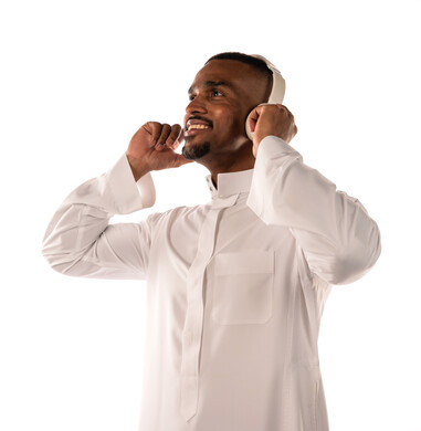 بورتريه لشاب اسمر عربي خليجي سعودي يضع سماعة لاسلكية على اذنه، الاستمتاع والمرح، بشرة سمراء، خلفية بيضاء