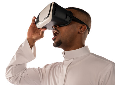 بورتريه لشاب أسمر عربي خليجي سعودي يرتدي نظارة الواقع الإفتراضي ثلاثية الأبعاد، يشاهد شيء ما بالواقع الإفتراضي، محاكاة العالم الافتراضي، خلفية بيضاء