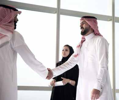 رجلان عربيان سعوديان يتصافحان بعد اجتماع عمل ناجح باللباس السعودي التقليدي  ، سكرتيرة أعمال في عباية سوداء , شركة سعودية ناجحة ، شركاء عمل ، بيئة عمل