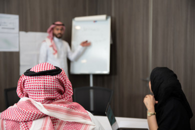 لقاء عمل لرجل اعمال سعودي خليجي يقدم افكاره للزملاء في المكتب على لوح ابيض ، فريق العمل يستمع لأفكار الاستثمارات  ، شركة سعودية ، بيئة عمل
