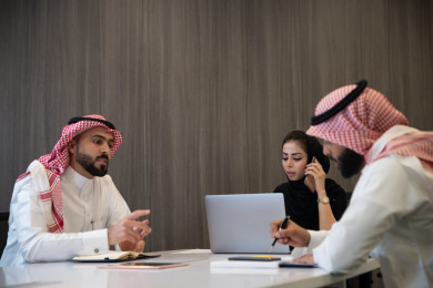 اجتماع رجال الاعمال السعوديون الخليجيون مع سيدة اعمال سعودية خليجية في مكتب العمل ، يتناقشون بالأعمال ، العمل على الكمبيوتر المحمول ، اجتماع فريق عمل ، شركة سعودية ، بيئة العمل 