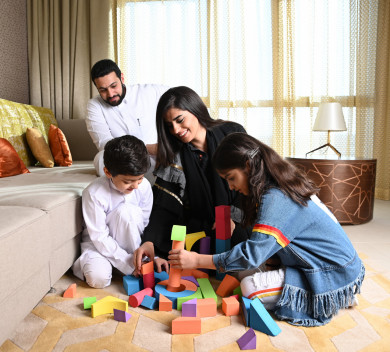 عائلة سعودية جميلة مجتمعين في غرفة المعيشة والأطفال يلعبنا على الأرض 