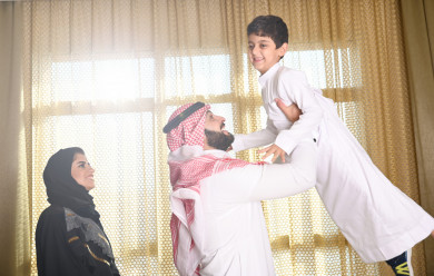 أب سعودي يلعب مع إبنه في غرفة المعيشة , عائلة سعودية صغيرة سعيدة 