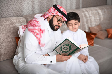 أب سعودي يقرأ القرآن مع إبنه في غرفة المعيشة 