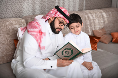 أب سعودي يقرأ القرآن مع إبنه في غرفة المعيشة 