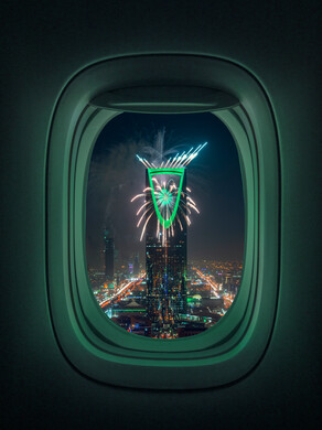 صورة لنافذة الطائرة تطل على برج المملكة في مدينة الرياض في المملكة العربية السعودية ، صورة جوية من داخل الطائرة لمركز المملكة ، العاب نارية للاحتفال باليوم الوطني السعودي ،  ابراج وناطحات سحاب في السعودية