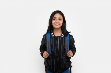 بورتريه لفتاه طالبة مدرسة سعودية مبتسمة تنظر الى الكاميرا ، ترتدي حقيبة ظهر مدرسية ، مدرسة سعودية