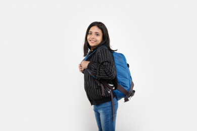 بورتريه لفتاه طالبة مدرسة سعودية مبتسمة تنظر الى الكاميرا ، ترتدي حقيبة ظهر مدرسية ، مدرسة سعودية