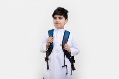 بورتريه لفتى طالب مدرسي سعودي مبتسم ، يرتدي حقيبة ظهر مدرسية ، و يرتدي ثوب سعودي تقليدي ،مدرسة سعودية