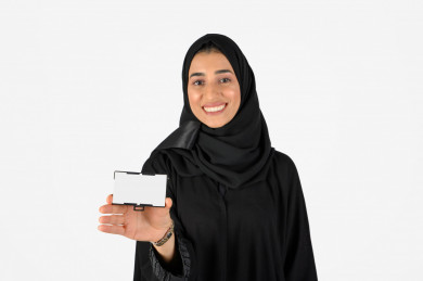 بورتريه بنت سعودية عربية خليجية ، طالبة مسلمة مع الحجاب، طالبة جامعية سعودية خليجية ، تمسك بيدها بطاقة تعريفية بيضاء، خلفية بيضاء