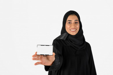 بورتريه بنت سعودية عربية خليجية ، طالبة مسلمة مع الحجاب، طالبة جامعية سعودية خليجية ، تمسك بيدها بطاقة تعريفية بيضاء، خلفية بيضاء