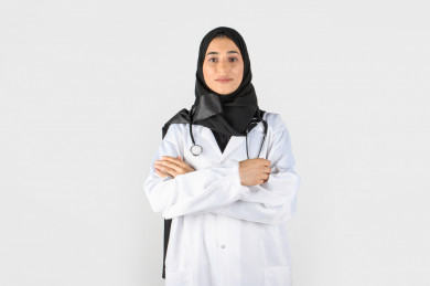 صورة مقربة لطبيبة تحمل سماعة طبيب ، بورتريه بنت طبيبة سعودية عربية مسلمة ، بخلفية بيضاء