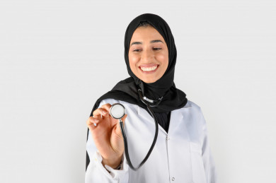صورة مقربة لطبيبة تحمل سماعة طبيب ، بورتريه بنت طبيبة سعودية عربية مسلمة ، بخلفية بيضاء