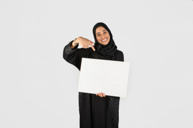 بورتريه بنت سعودية خلف لوحة بيضاء صغيرة فارغة ، لوحة فارغة ، بنت خليجية تحمل لوح ابيض ، بخلفية بيضاء